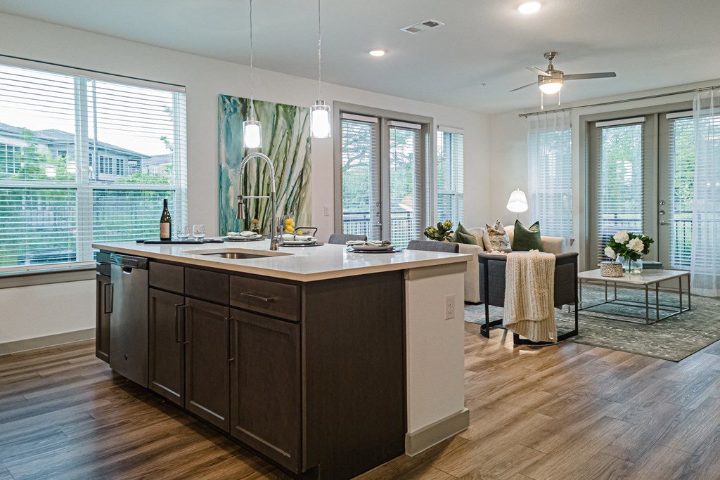 a kitchen with a large island and a living room in the background