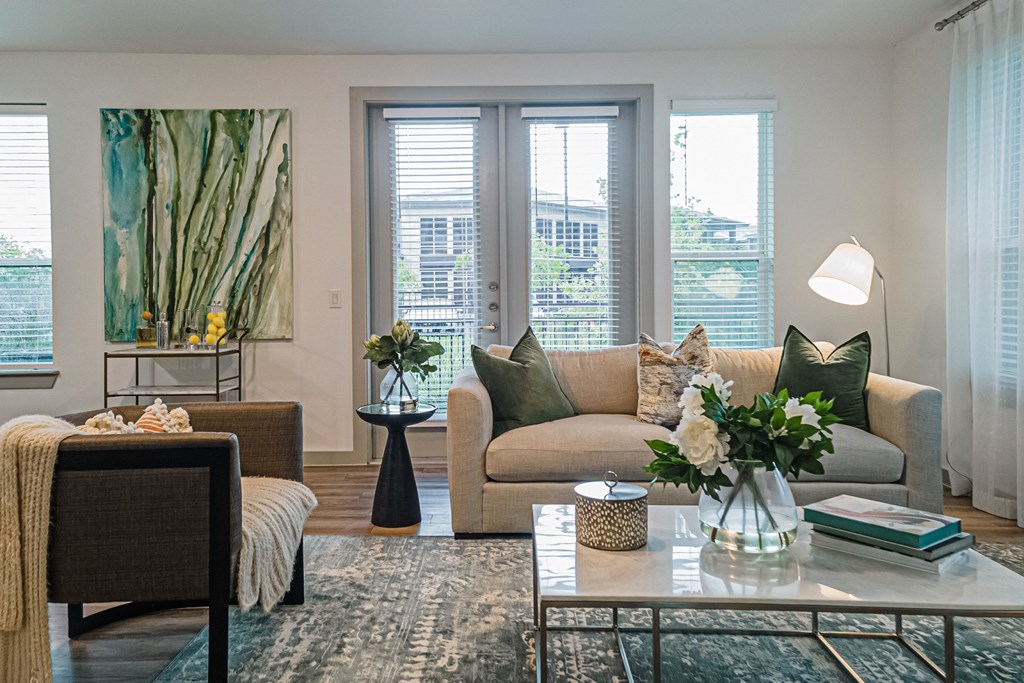 a living room with beige couches and a coffee table with a vase of flowers