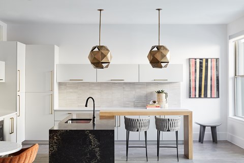 A kitchen with a black marble island and a dining table with four chairs.