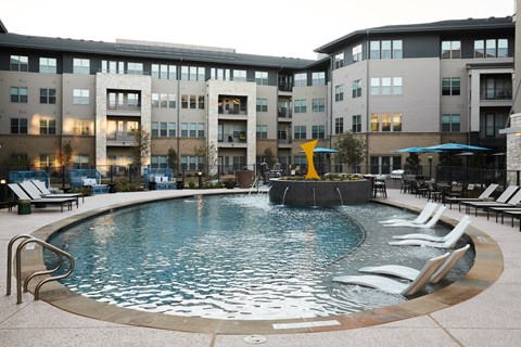 A round swimming pool with a waterfall in the middle of it.