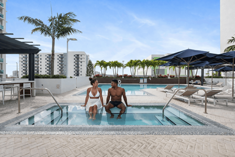 Two people are sitting in a pool on a sunny day.