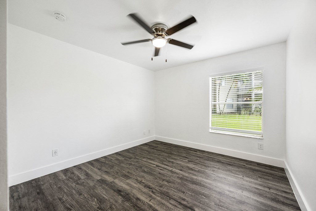 an empty living room with a ceiling fan and a window