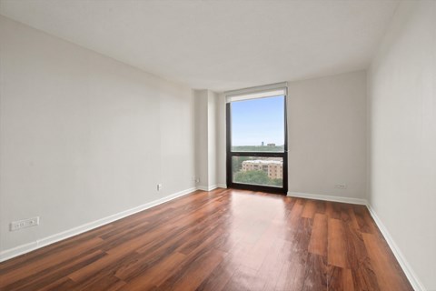 A bedroom with wooden floors and floor to ceiling windows.
