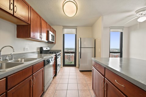 A kitchen with brown cabinets and a stainless steel refrigerator.