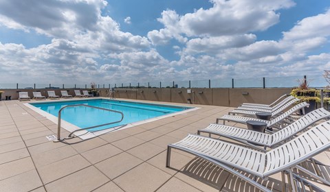 A pool with a metal railing and sun loungers.