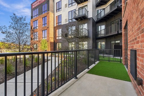 A balcony with a black railing and a green artificial grass area.