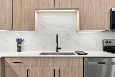 A kitchen with wooden cabinets and a marble backsplash.