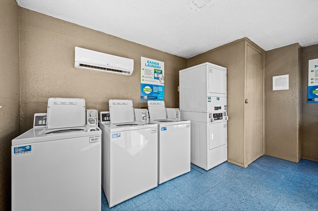 four sets of washing machines and refrigerators in a utility room with a row of