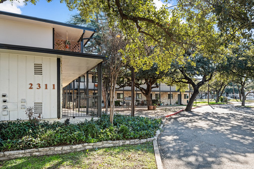 a building with a yard and trees in front of it