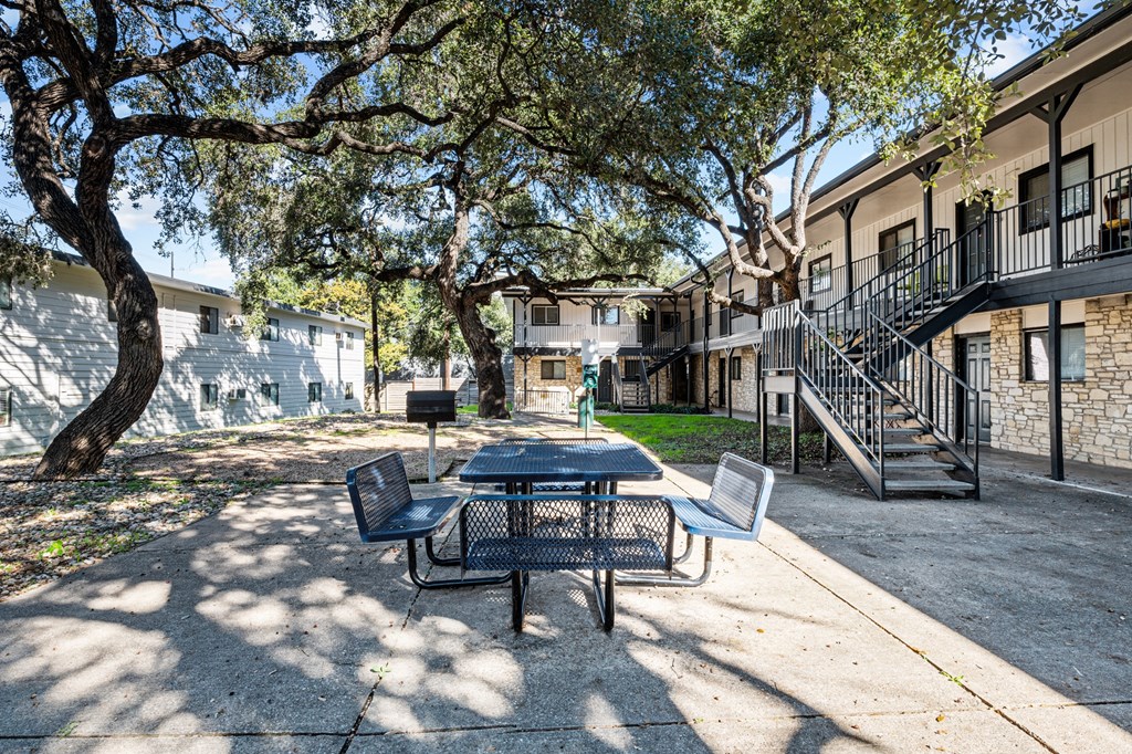 our apartments have a patio with a table and chairs and trees