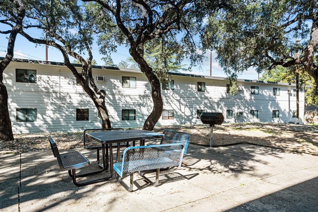 a patio with a table and chairs in front of a building