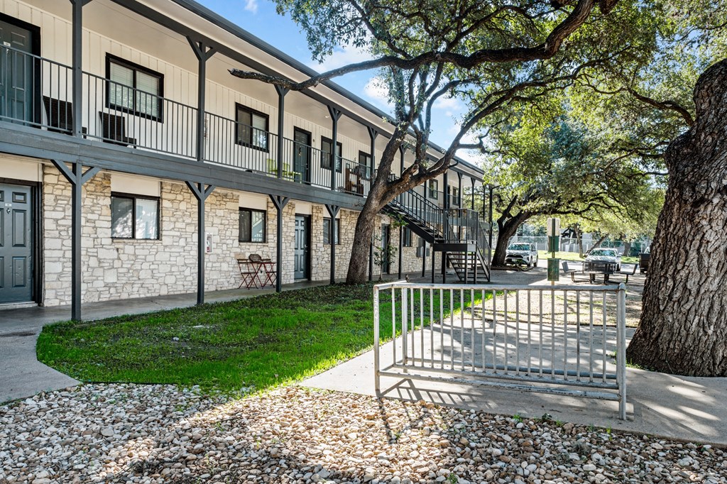 a metal gate in front of a building with trees