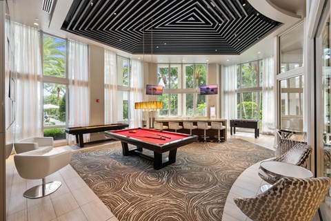 a billiards table in a room with windows