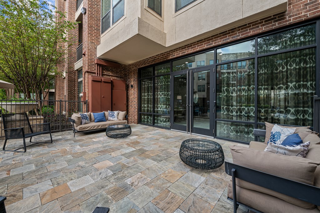 a patio with two couches and chairs in front of a building