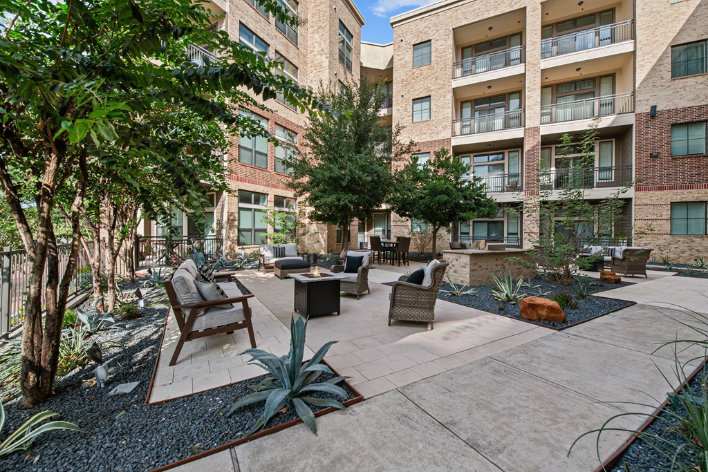 a courtyard with a seating area and trees in front of an apartment building