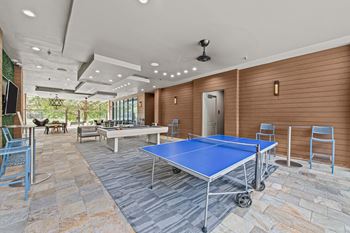 A blue ping pong table is in the middle of a room with a stone floor.