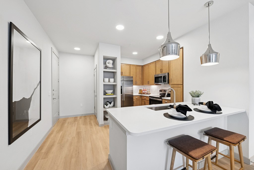 A modern kitchen with a white countertop and wooden flooring.