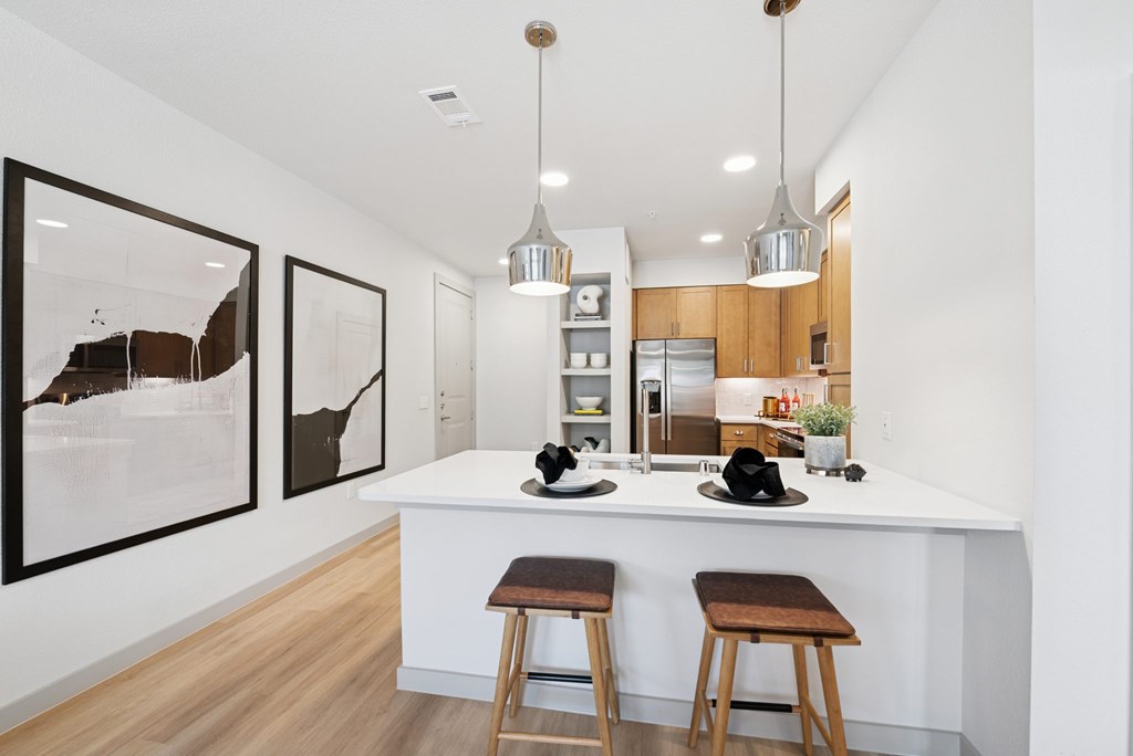 A kitchen with a white counter and brown stools.