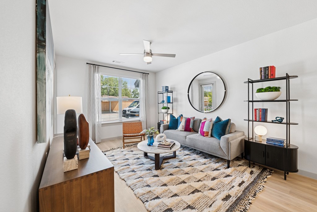 A living room with a grey couch, a coffee table, a bookshelf, and a painting on the wall.