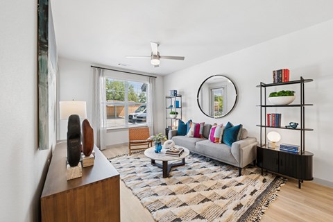 A living room with a grey couch, a coffee table, a bookshelf, and a painting on the wall.
