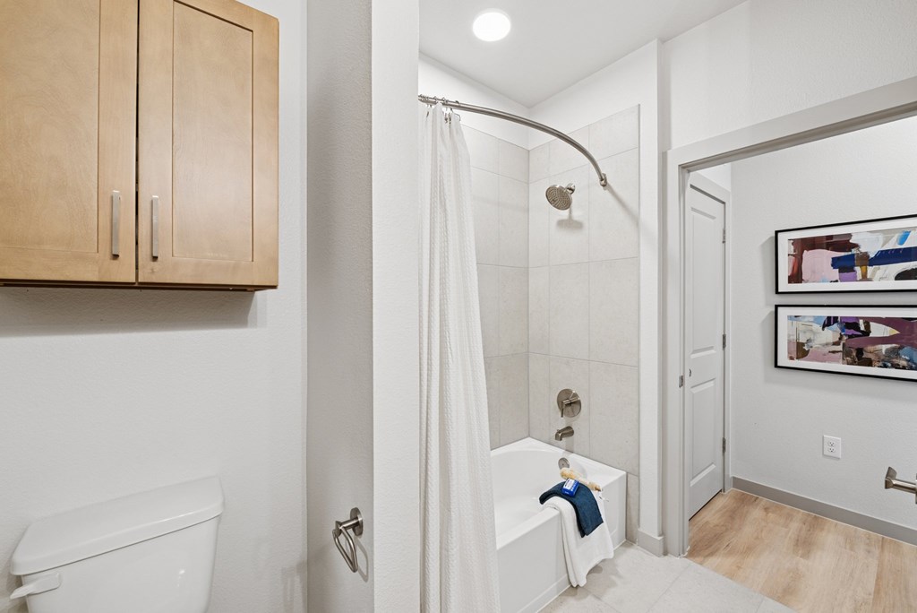 A white toilet sits next to a white bathtub in a bathroom.