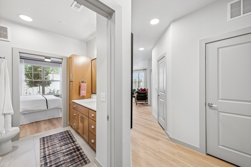 A white bedroom with a window and a wooden cabinet.