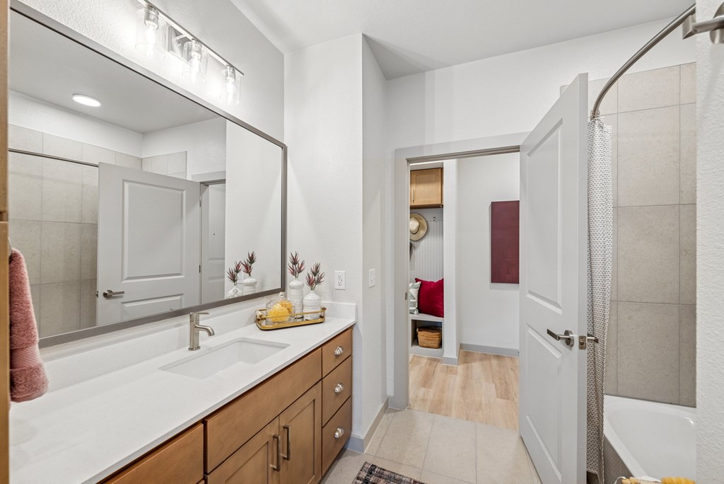A bathroom with a sink, mirror, and shower.