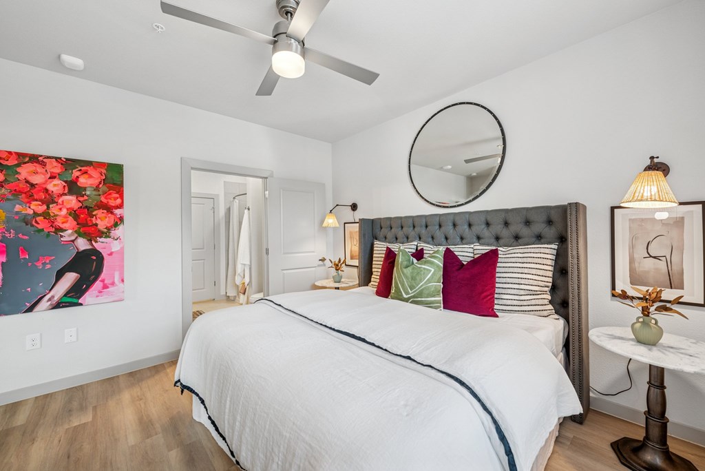 A bedroom with a large bed and a painting on the wall.