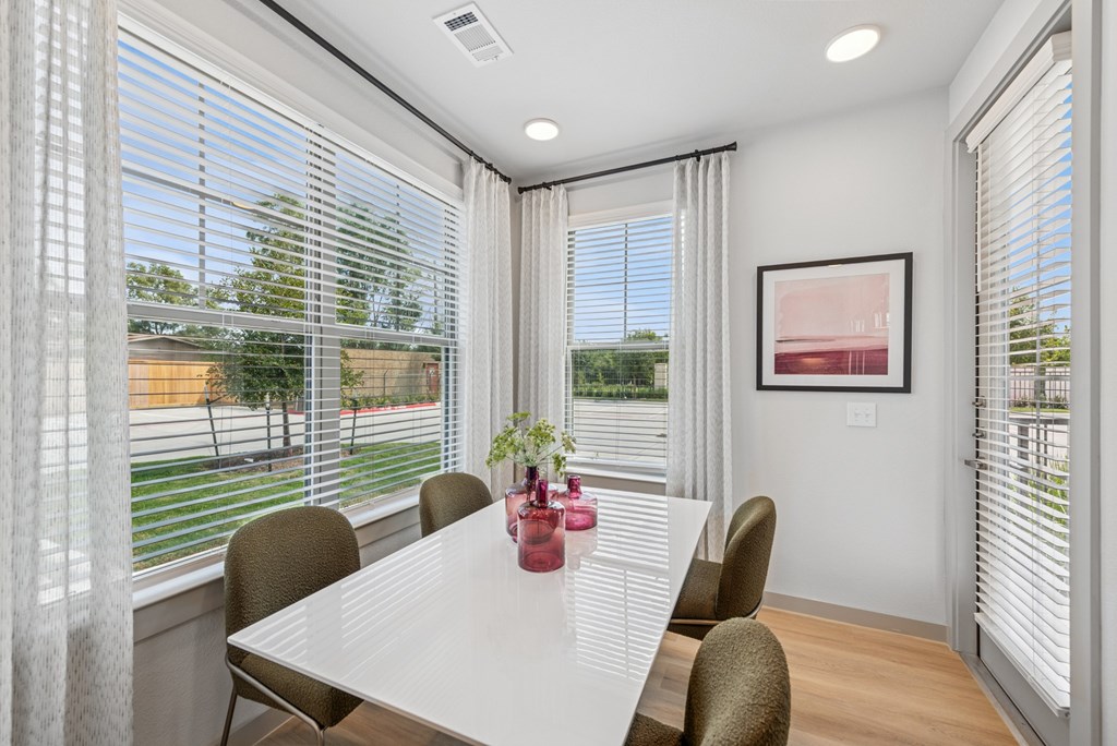 A dining room with a table, chairs, and a window with blinds.