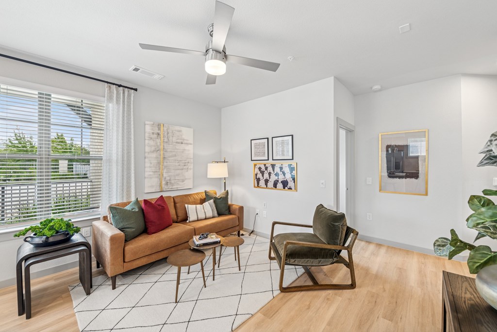 A living room with a brown couch, a chair, and a table with a potted plant on it.
