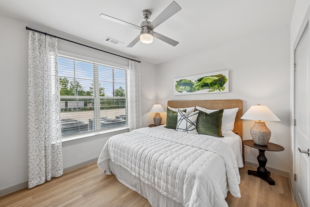 A bedroom with a large bed and a ceiling fan.