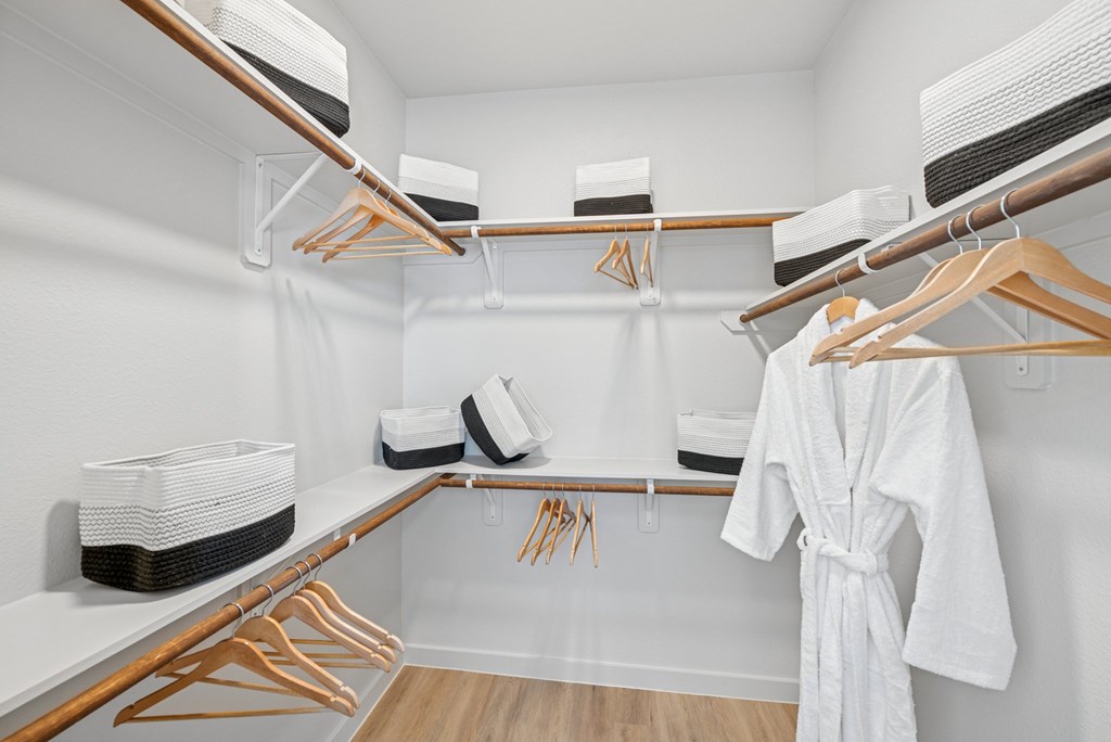 A white bathrobe is hanging on a rack in a white bathroom.
