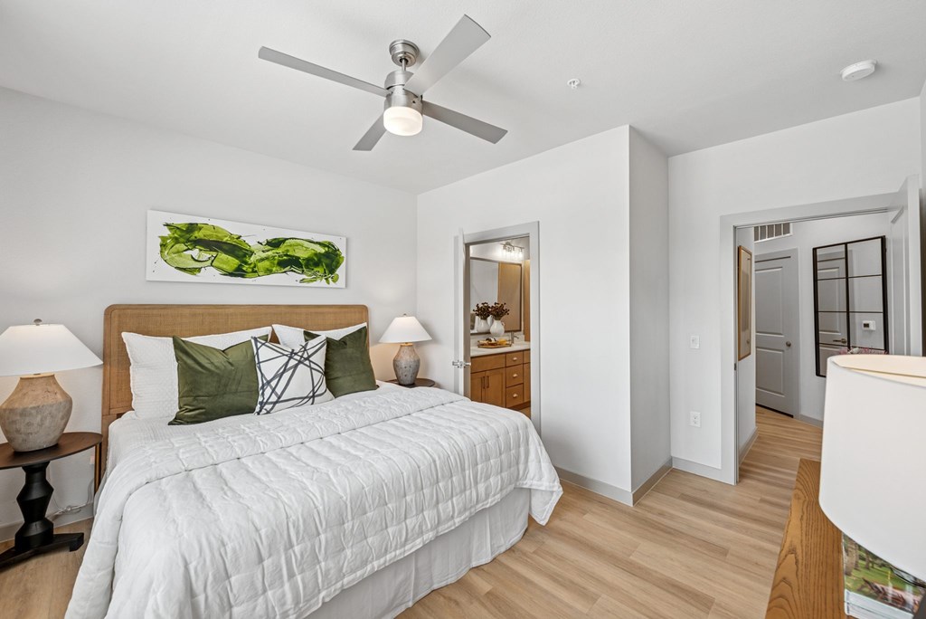 A bedroom with a large bed and a ceiling fan.