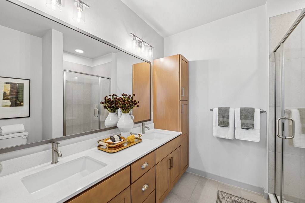 A bathroom with a sink, mirror, and shower.