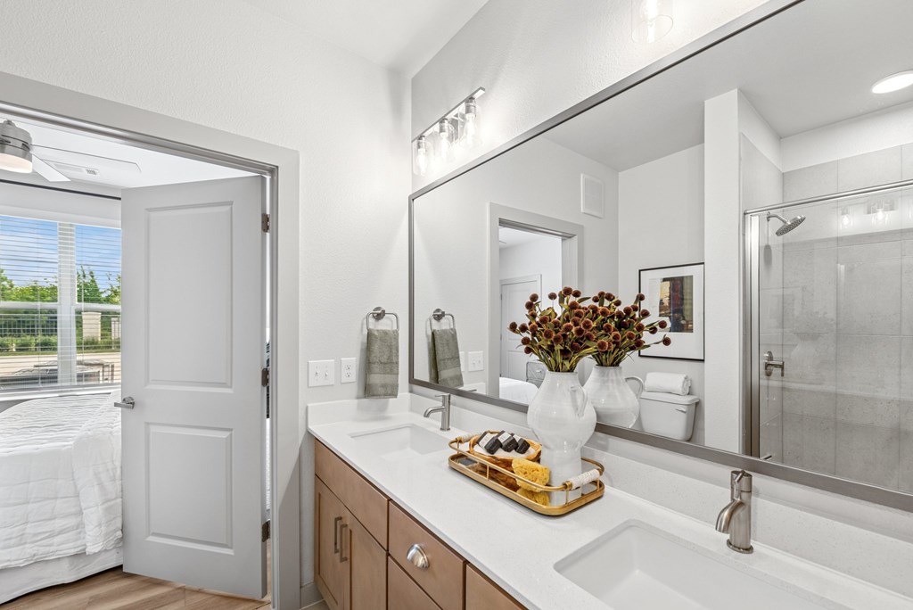 A white bathroom with a large mirror and a tray of food on the counter.