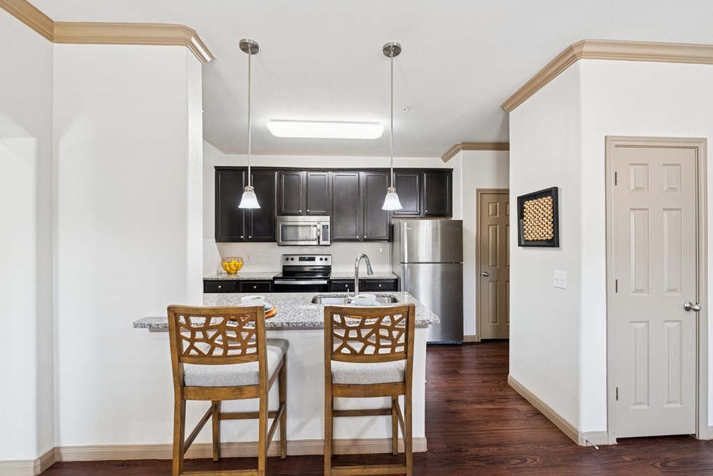 A kitchen with a table and two chairs.