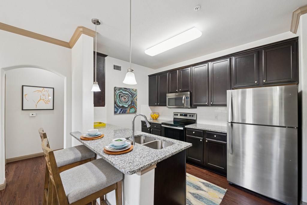 A kitchen with a stainless steel refrigerator and a dining table with chairs.