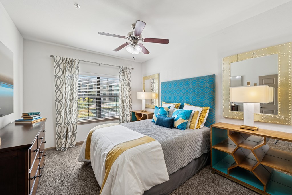A bedroom with a large bed and a ceiling fan.