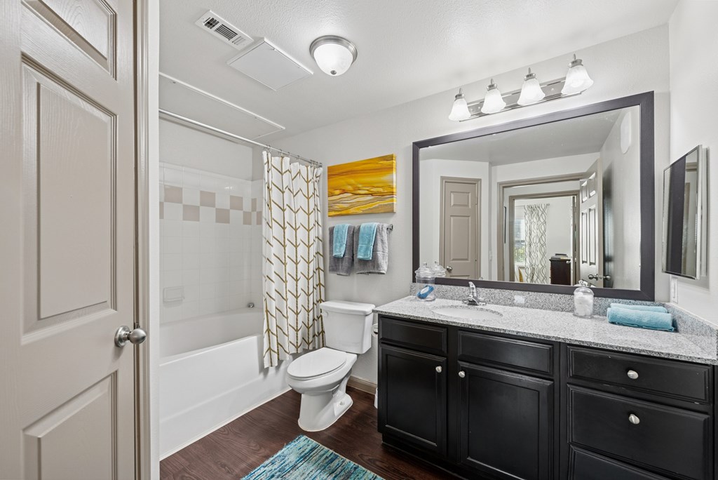 A bathroom with a toilet, sink, and mirror.
