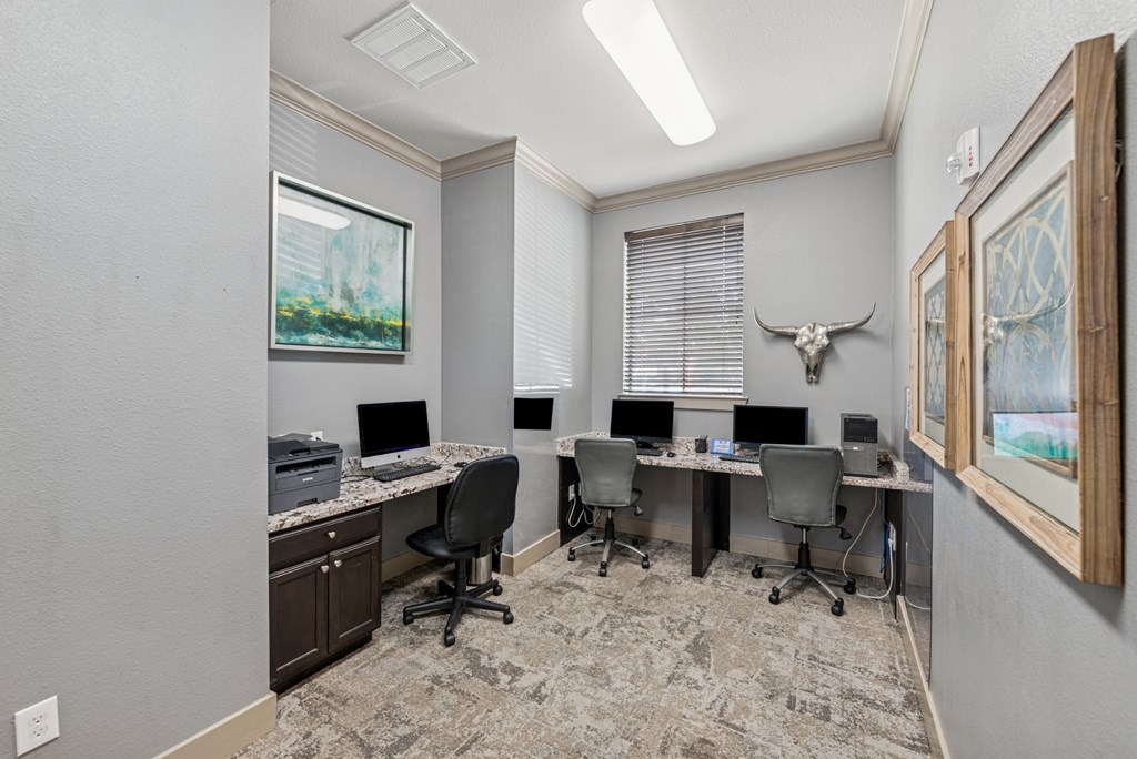 A room with a desk, chairs, and a painting on the wall.