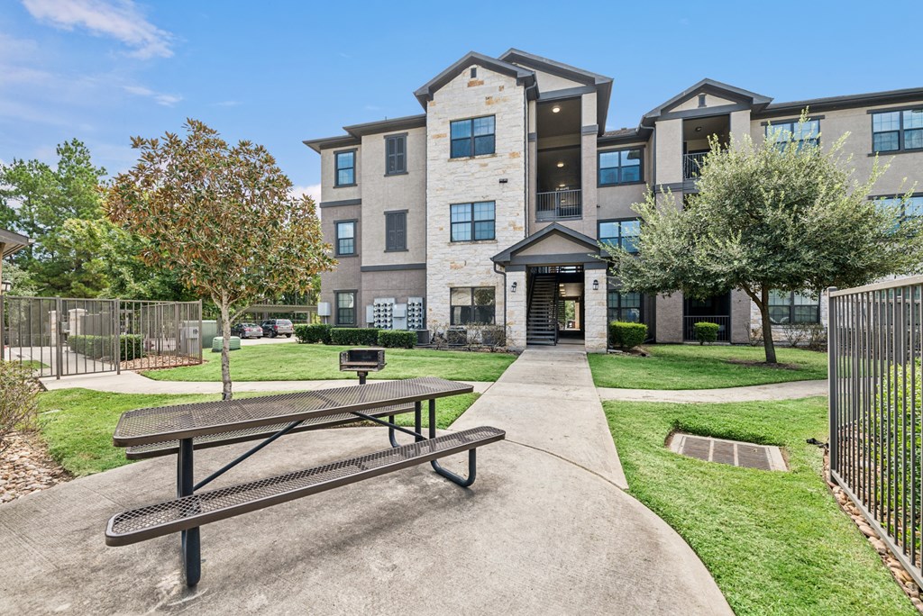 A large apartment complex with a picnic table in front.