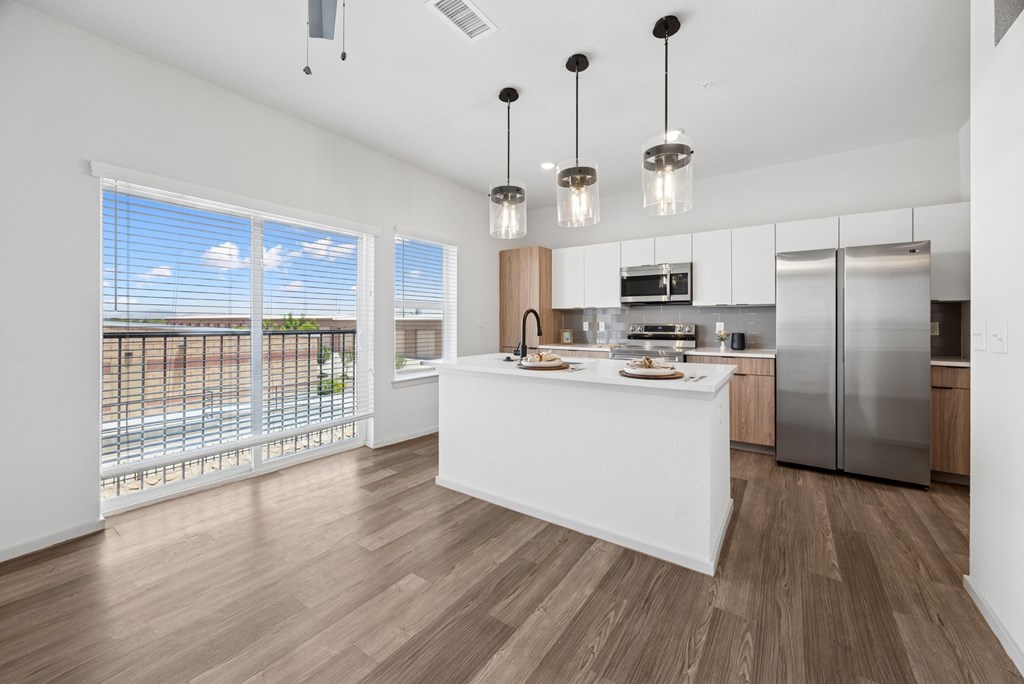 A modern kitchen with a white island and stainless steel appliances.