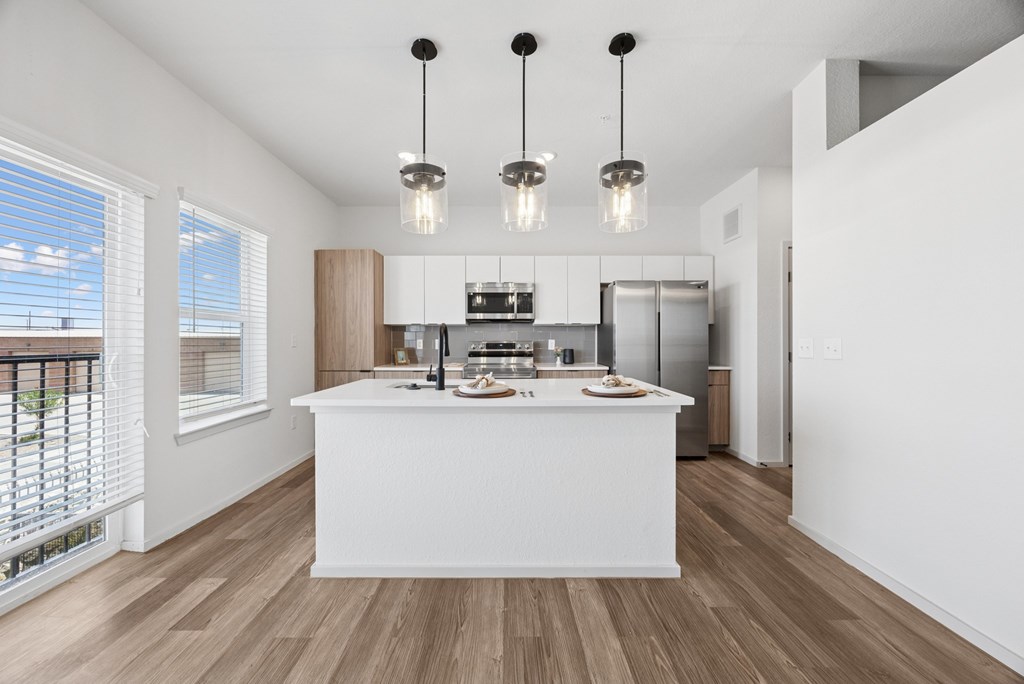 A modern kitchen with a white island and wooden floors.