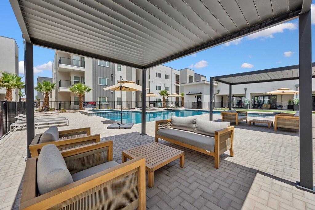 A patio with a pool and lounge chairs.