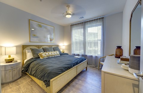 A bedroom with a bed, nightstand, and a painting on the wall.
