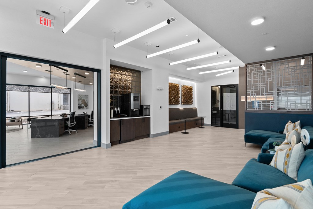 a lobby with blue couches and a reception area with a glass door
