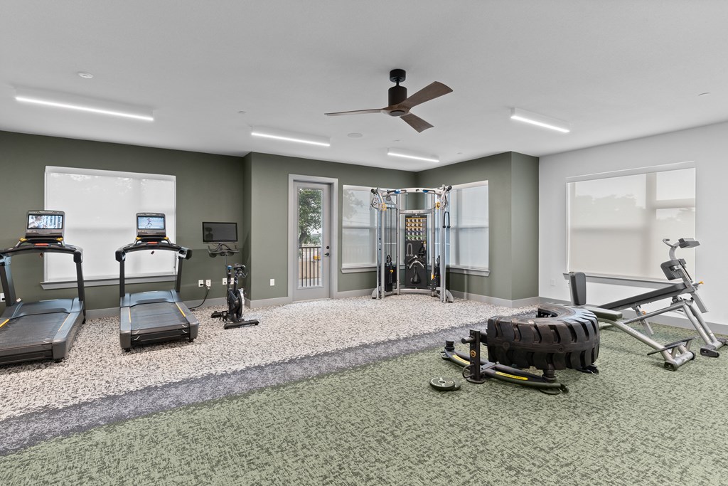 a gym with treadmills and other exercise equipment in a home with green walls
