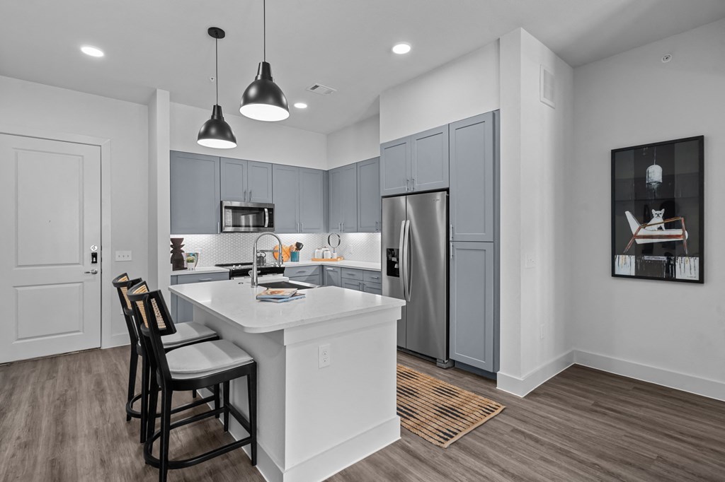a kitchen with a large island and a stainless steel refrigerator