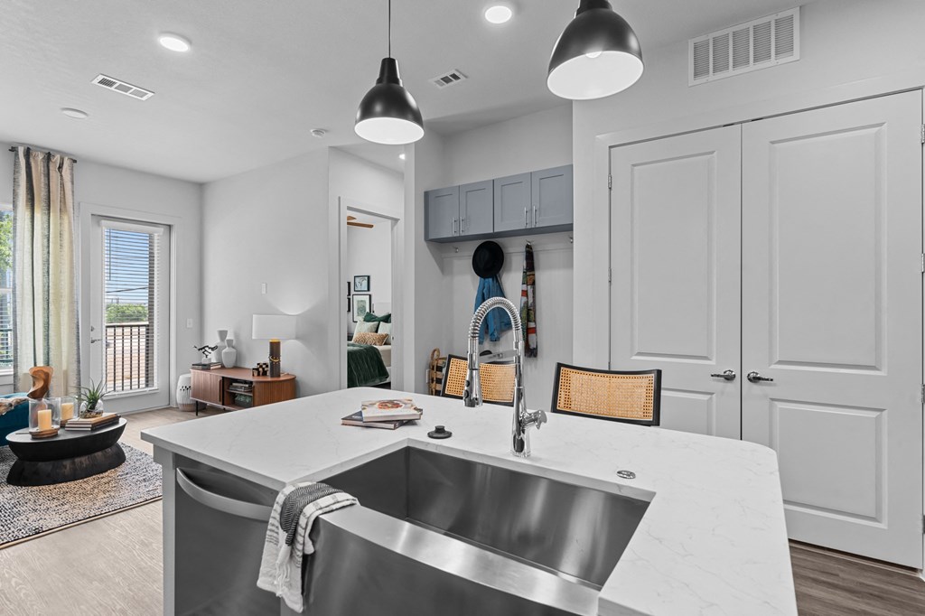 an open kitchen and living room with white cabinets and a large sink