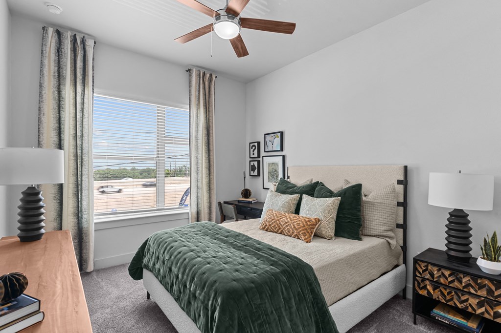 a bedroom with a large window and a ceiling fan